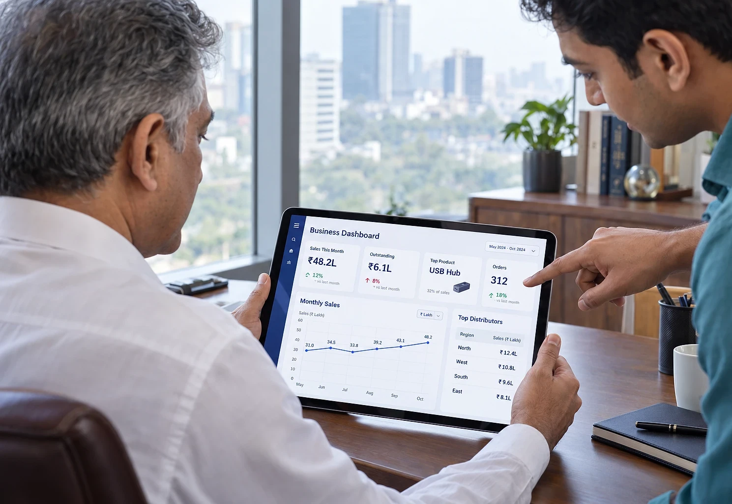 Trading business owner and a colleague reviewing sales and distributor figures on a tablet